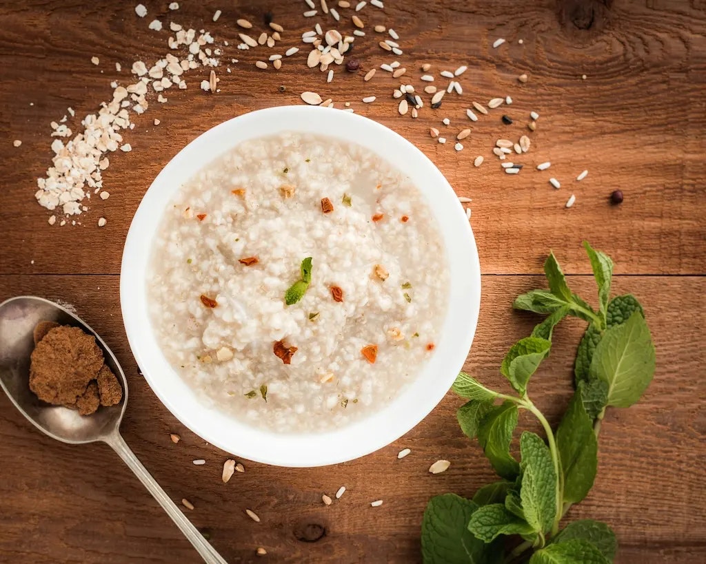 Porridge und ein paar Gewürze auf einem Holztisch.