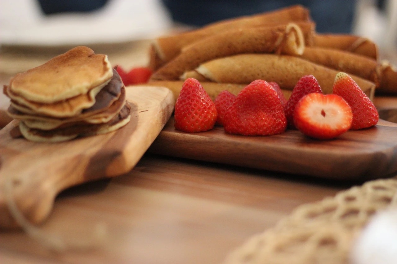 Pancakes und Erdbeeren auf einem Brett.