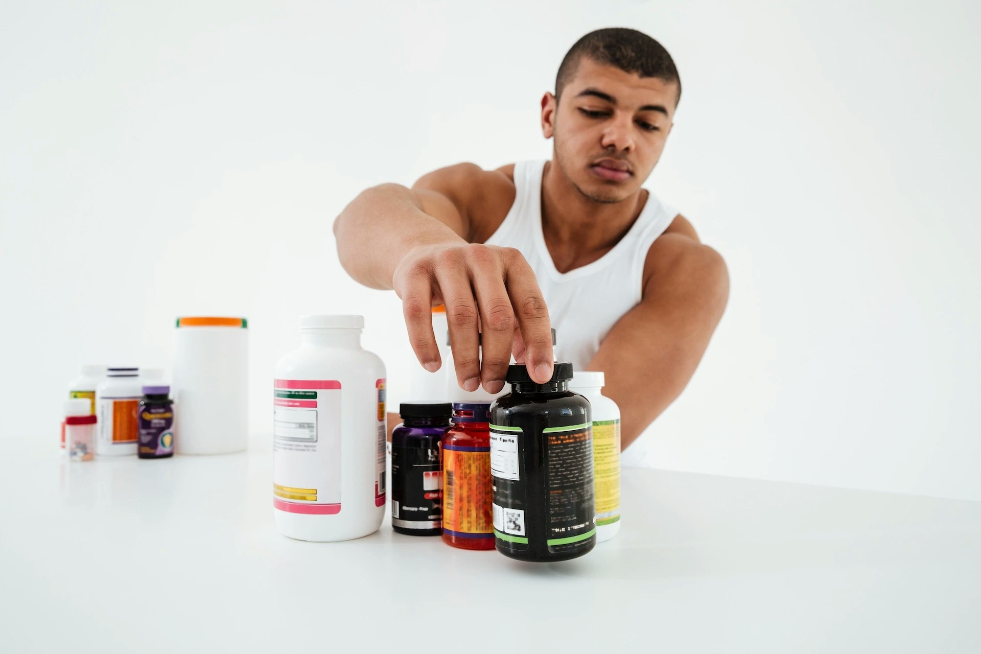 Ein Mann und mehrere Supplements auf einem weißen Tisch.