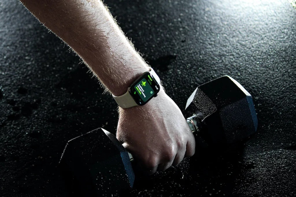 Ein Arm mit einer Smartwatch und eine Kurzhantel in der Hand.