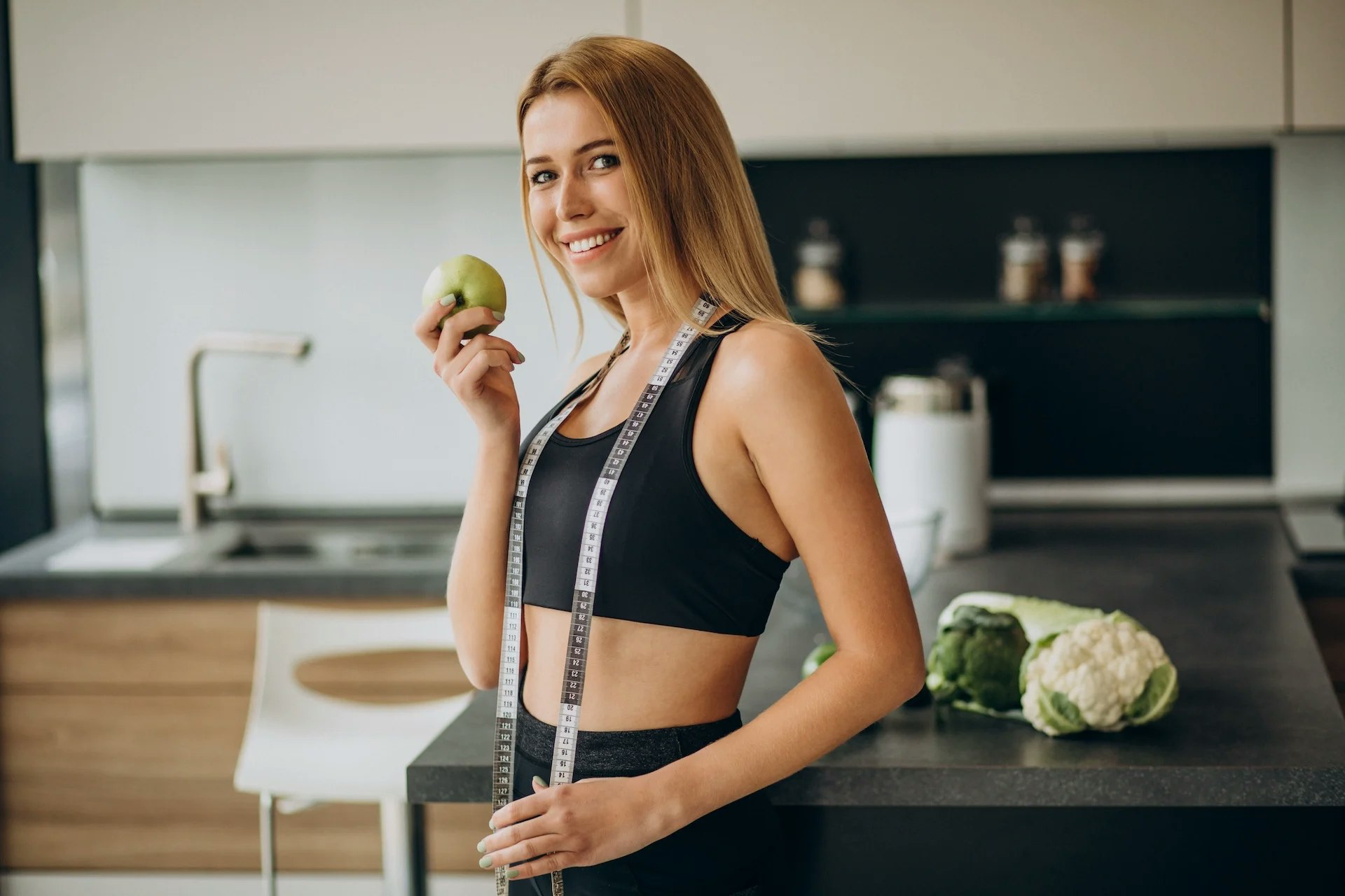 Bild von einer sportlichen Frau mit einem Apfel und einem Maßband.
