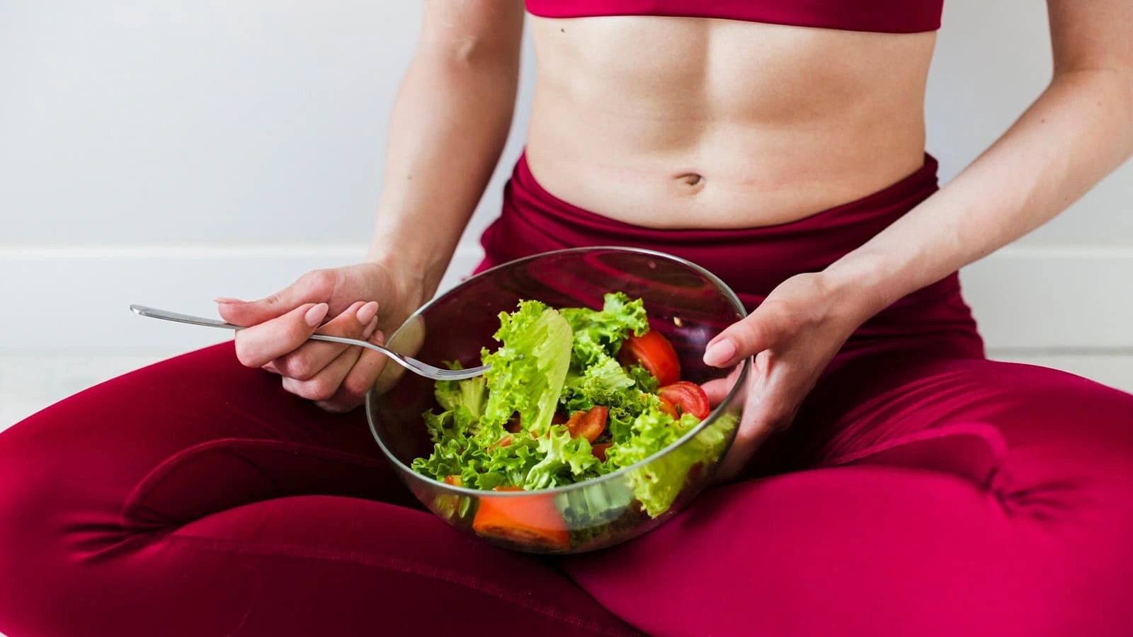Bild von einer sportlichen Frau mit einer Schüssel voller Salat.