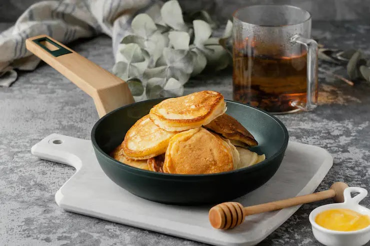 Eine Pfanne mit Low Carb Pancakes und einer Tasse Tee im Hintergrund.