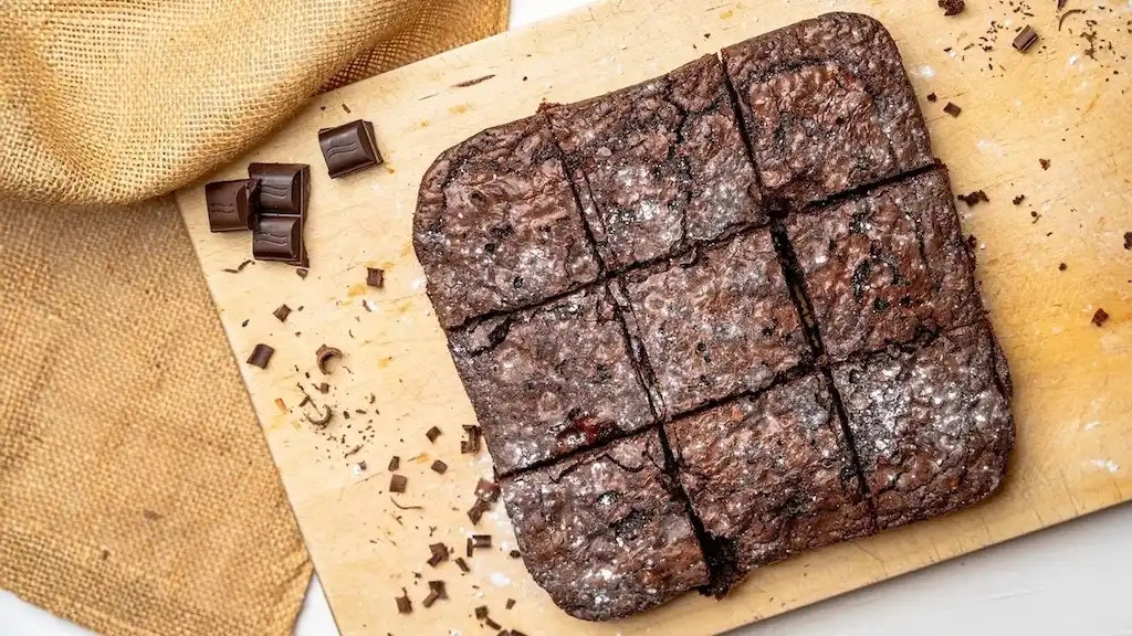Brownies und Schokolade auf einem Holzbrett.
