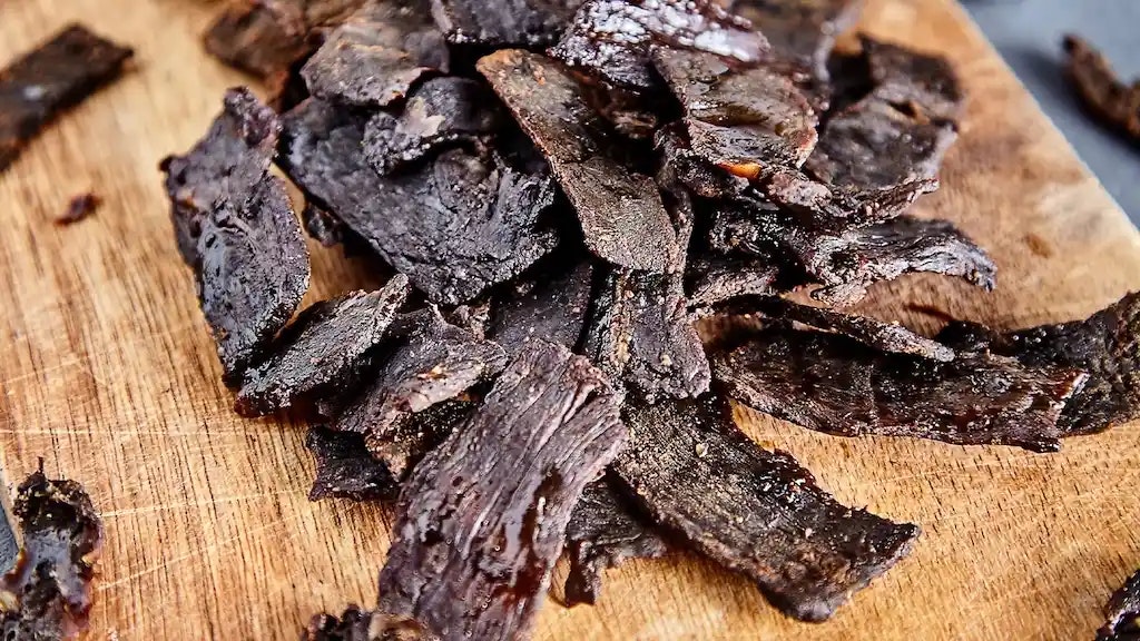 Wie gesund ist Beef Jerky? Bild von Beef Jerky auf einem Holzbrett.