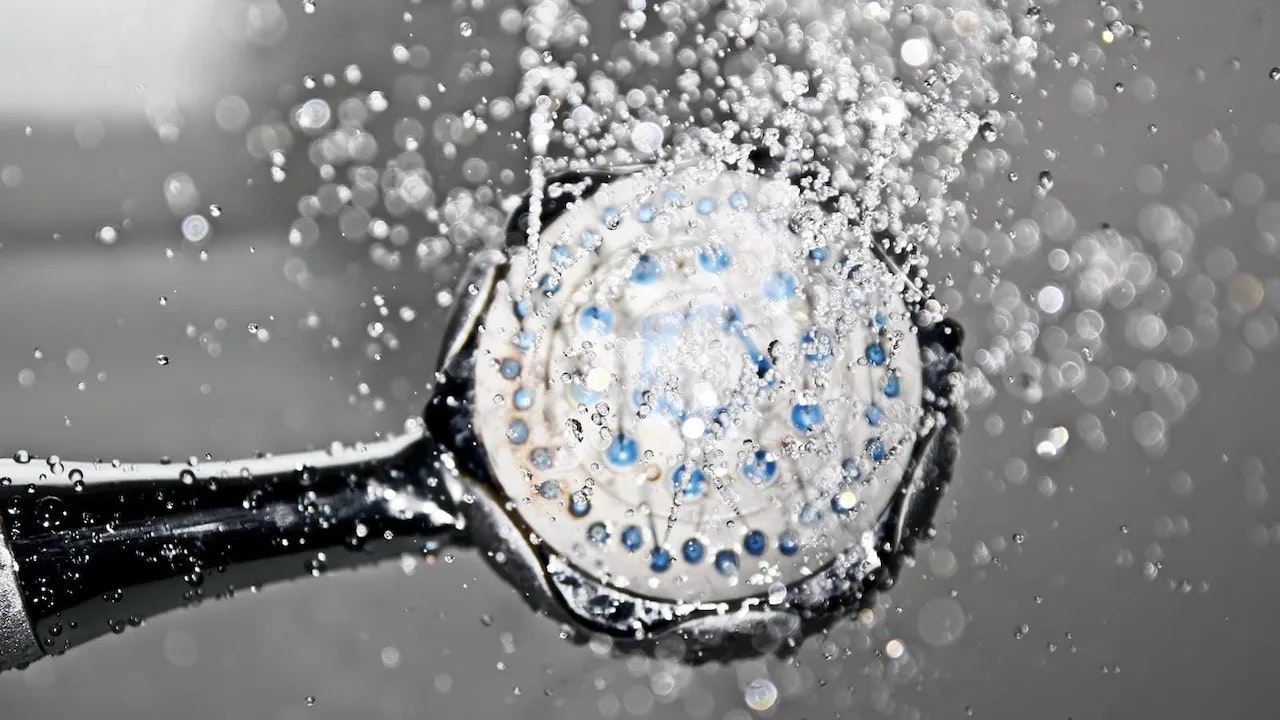 Bild von einem Duschkopf aus dem Wasser strömt.