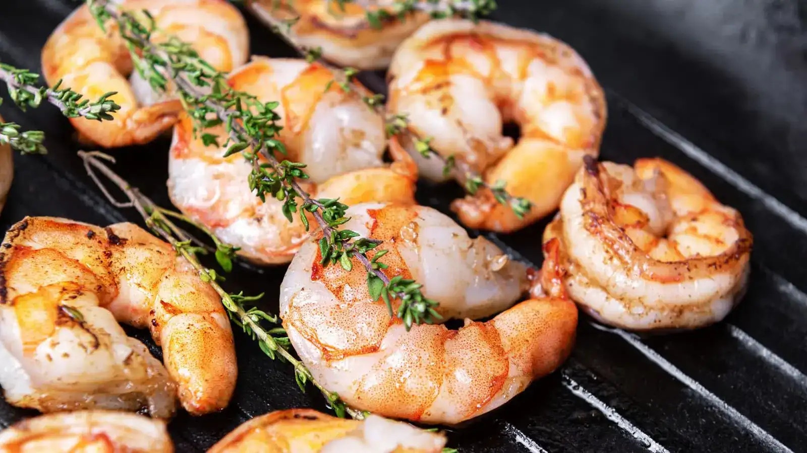 Garnelen und Kräuter auf einem Grill.