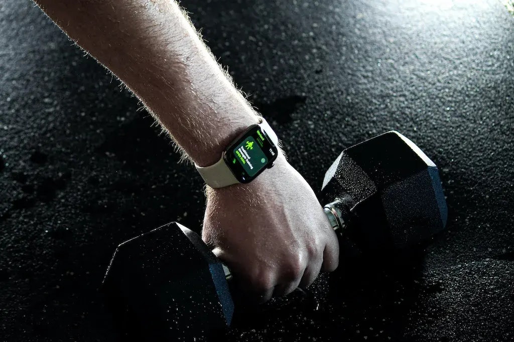 Ein Arm mit einer Smartwatch und eine Kurzhantel in der Hand.