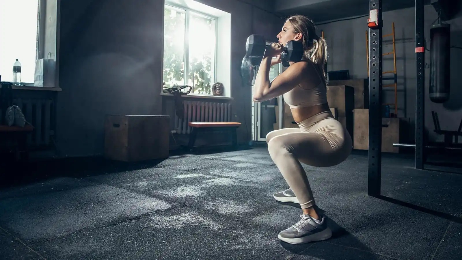 Eine Frau, die Squats mit zwei Kurzhanteln in den Händen durchführt.