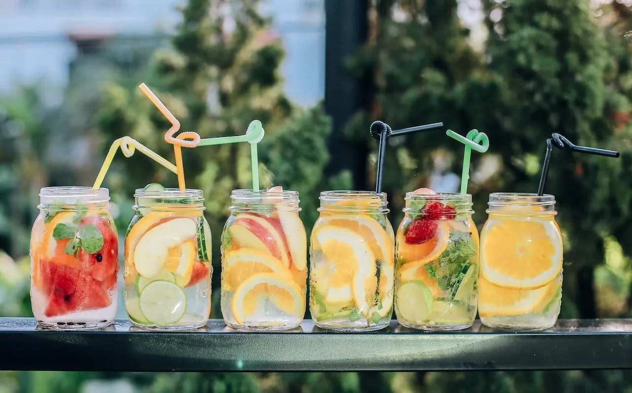 Mehrere Gläser mit Wasser und Früchten.