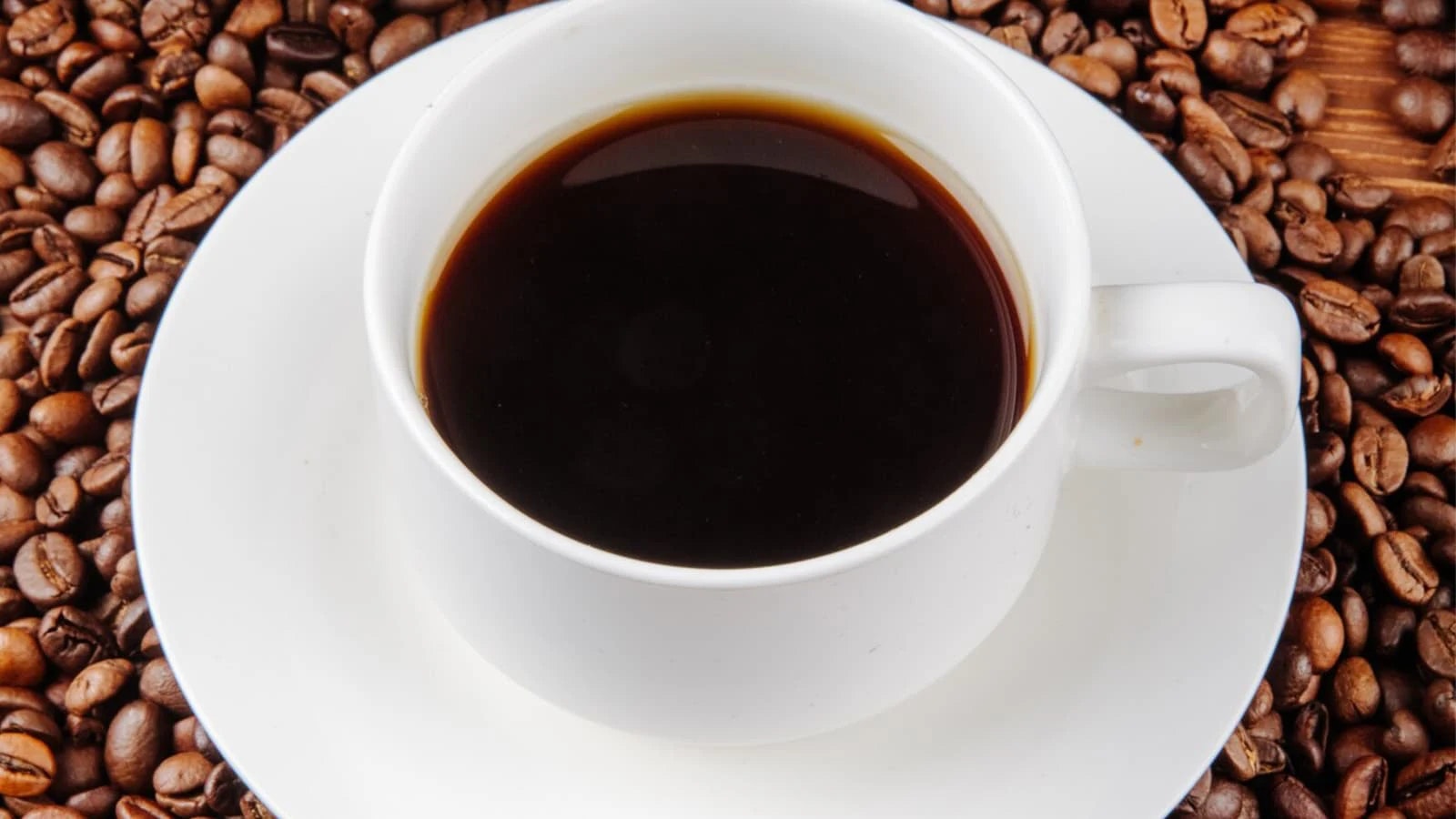Eine Tasse Kaffee auf einem Haufen an Kaffeebohnen