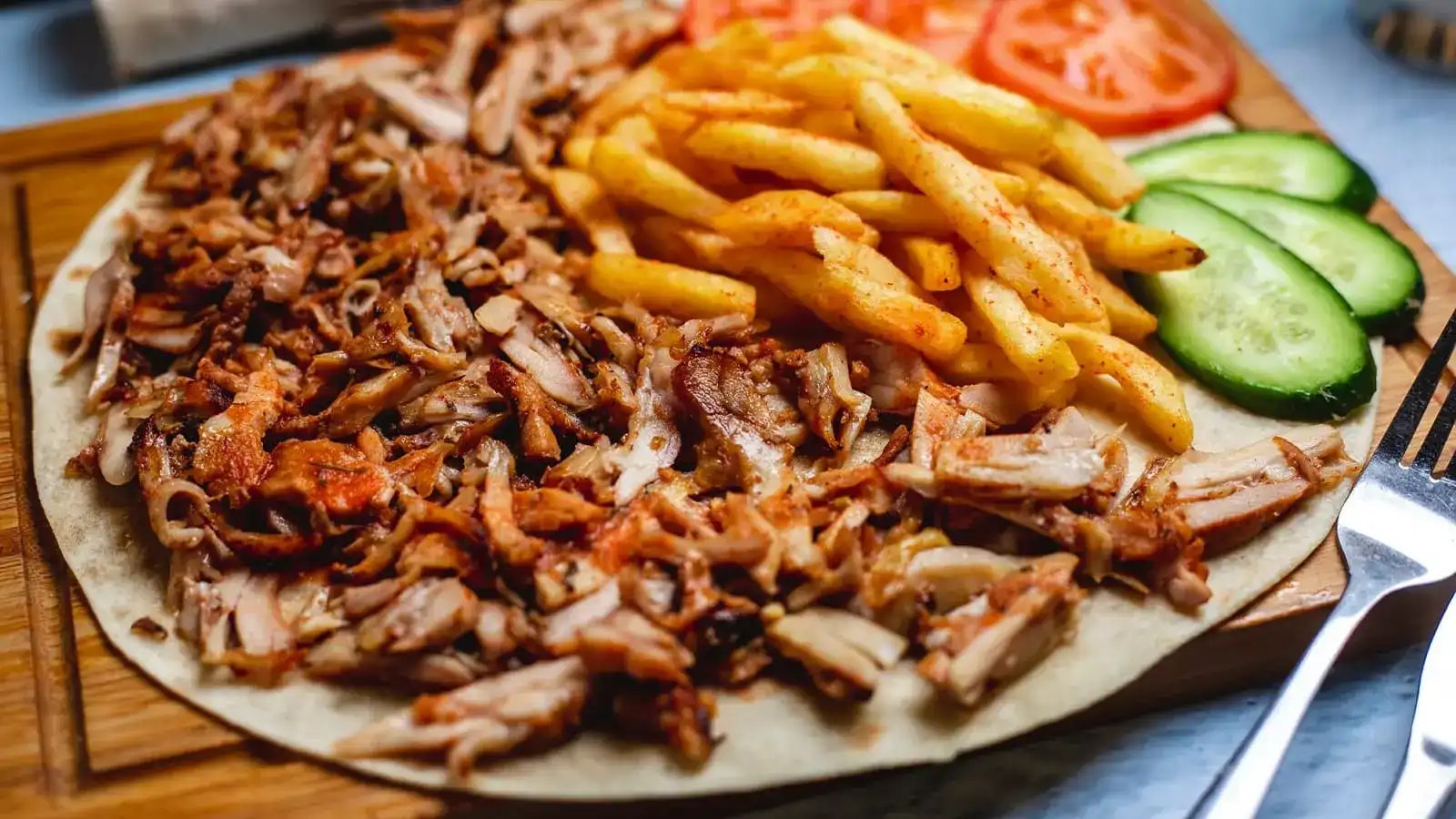 Dönerfleisch, Pommes und Gemüse auf einem Fladenbrot.