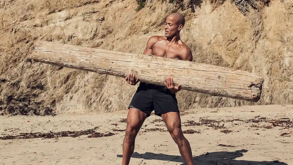 Bild von David Goggins mit einem Holzstamm in den Händen.