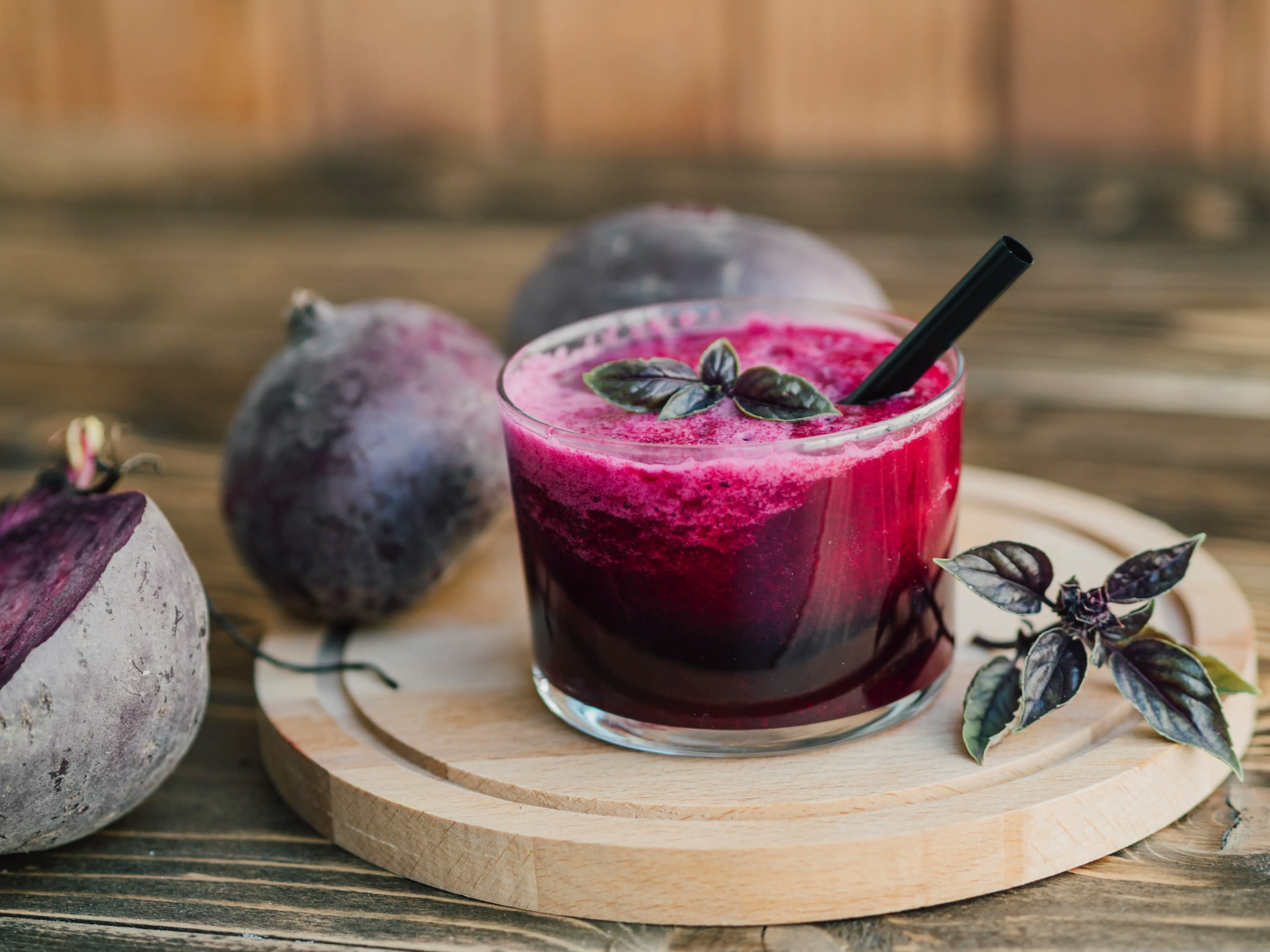 Ein Glas mit Rote Beete Saft auf einem Holzbrett.