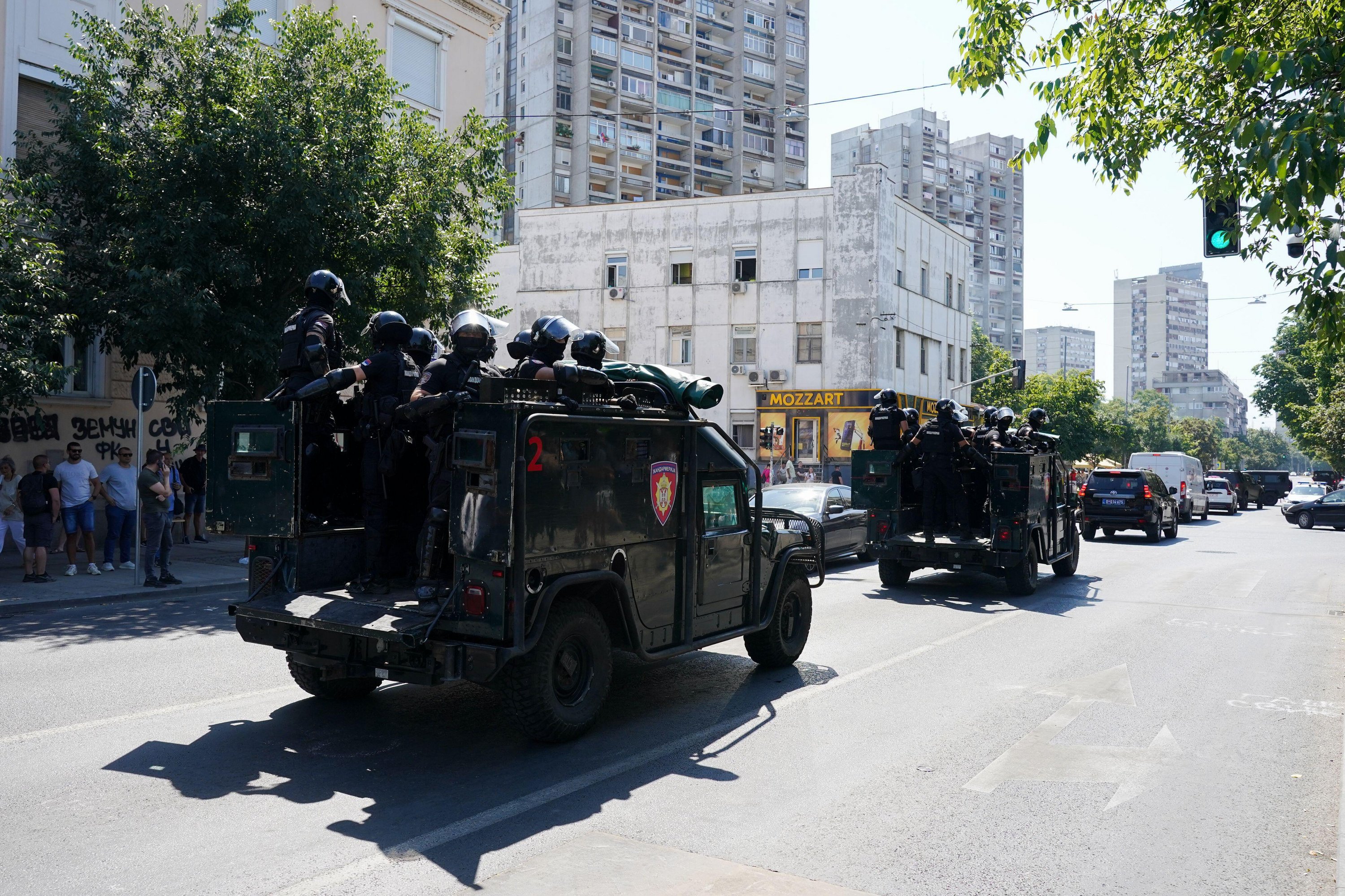 Several police armoured vehicles with policemen in the trunk, driving in the streets of Belgrade