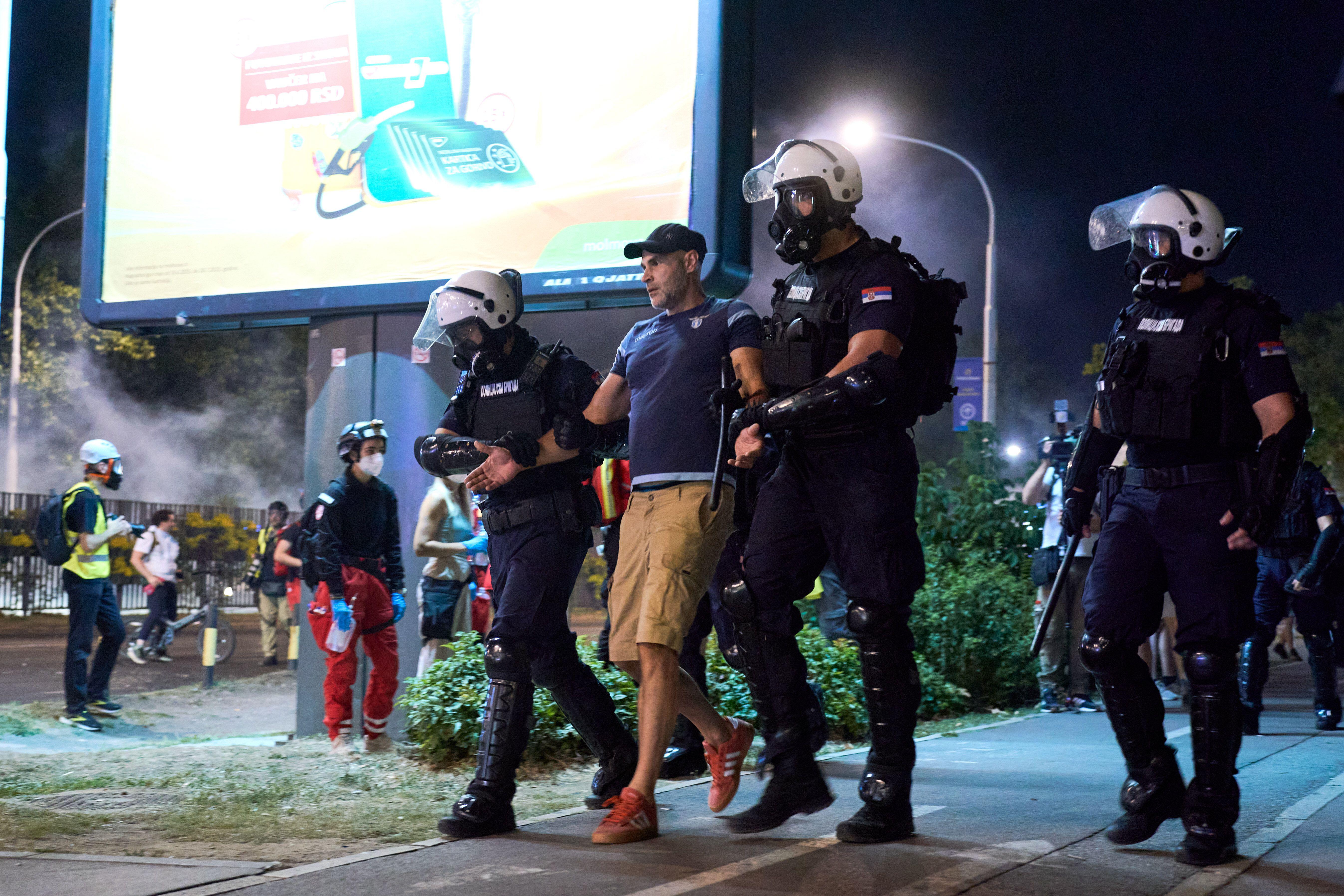 In the streets of Belgrade, two policemen are standing holding a civilian