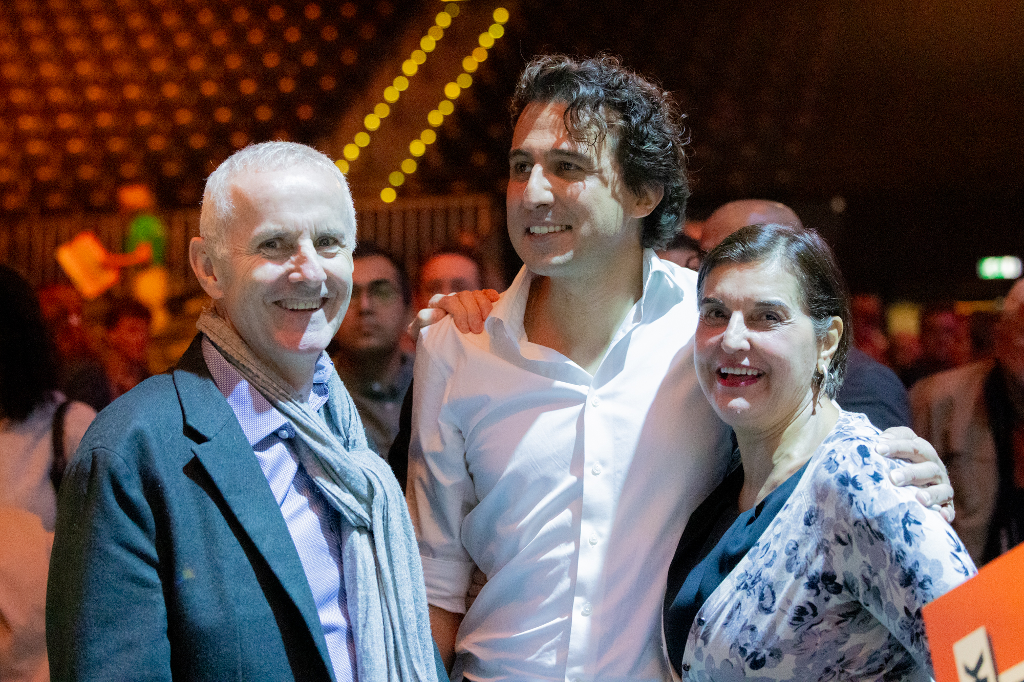 Jesse Klaver is standing between Ciarán Cuffe and Vula Tsetsi, all three smiling in the Congress room