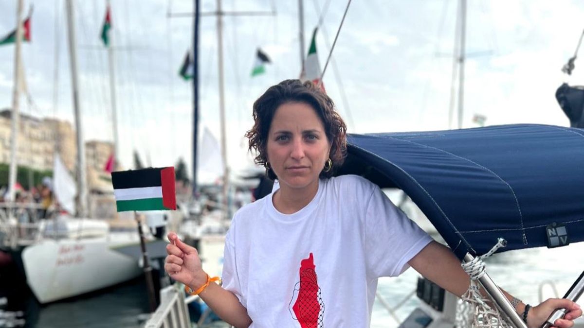 Benedetta Scuderi on a docked sailboat holding a small Palestinian flag.