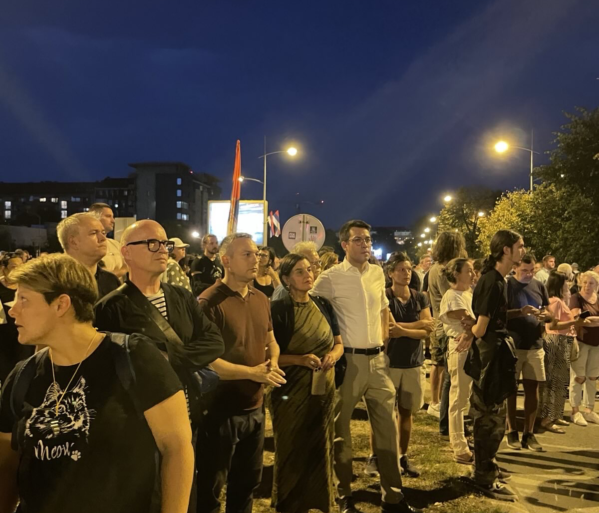 EGP Committee members and co-chair with co-presidents of the Serbian Green-Left Front, standing in a crowd at night in a city park during a protest