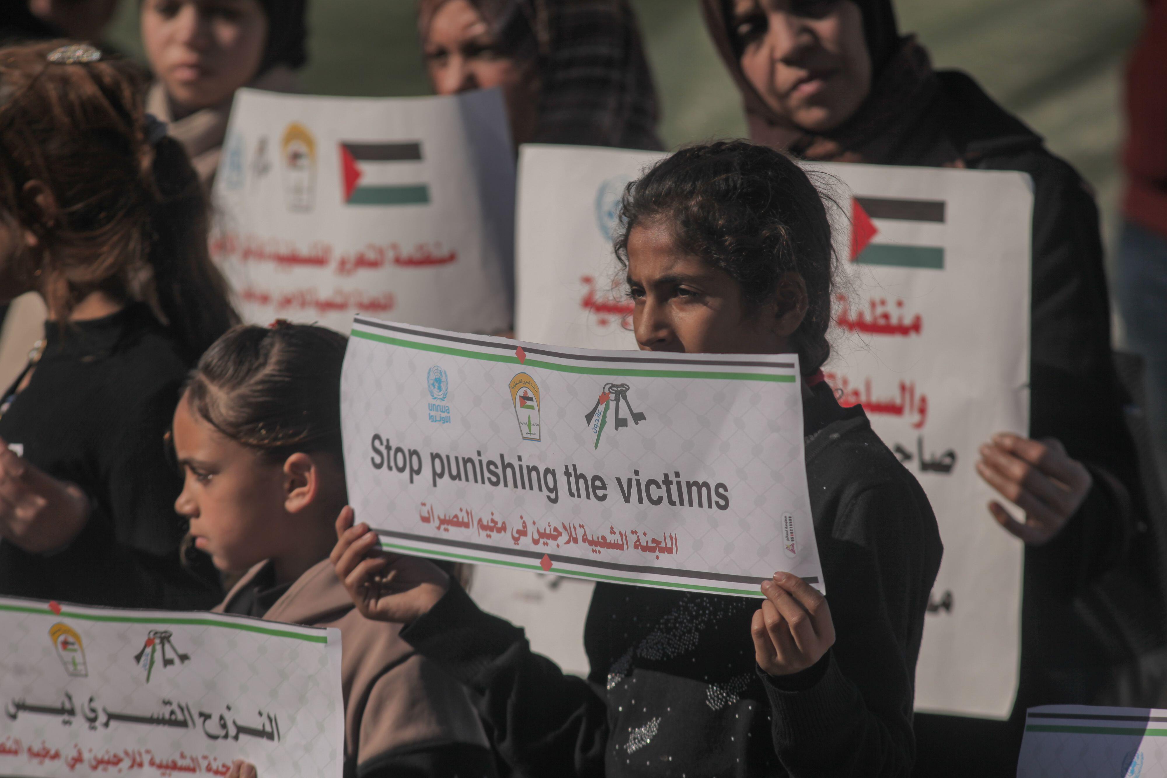 Young girl holding a sign reading "Stop punishing the victims".