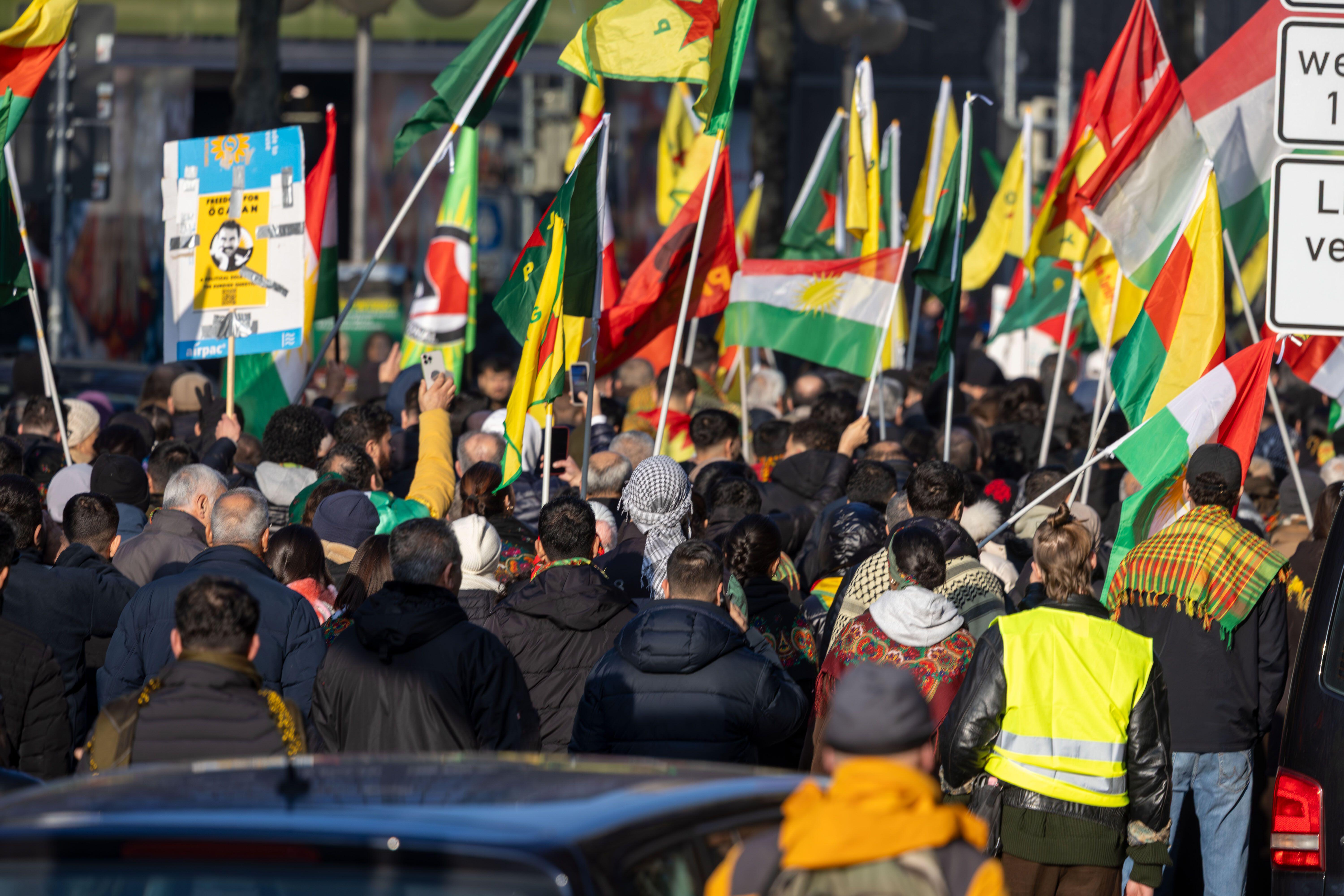 Group of people in the streets holding Kurdish flags and Rojavan flags