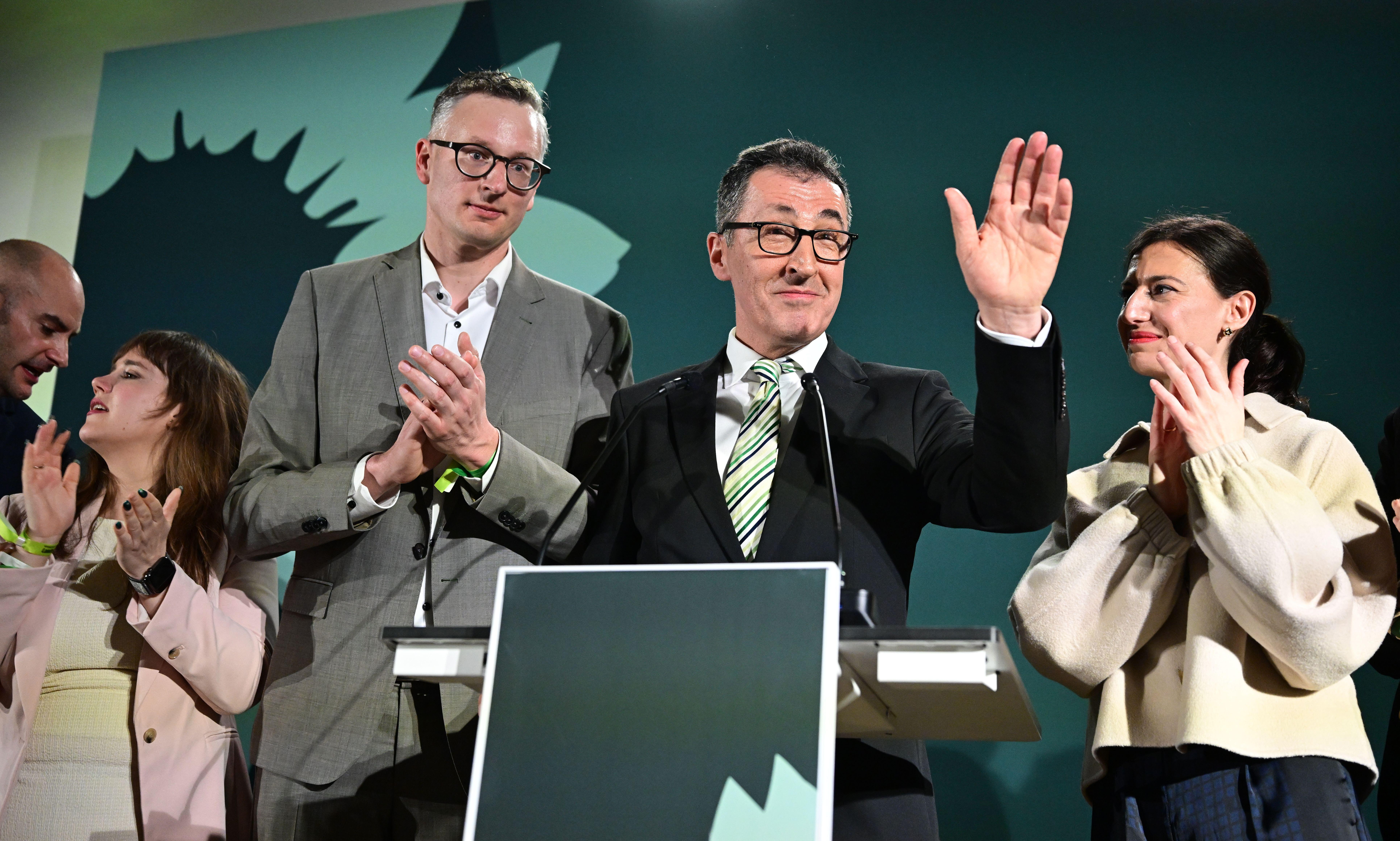 Stuttgart, Germany. 08th Mar, 2026. Cem Özdemir (Alliance 90/The Greens, M), lead candidate in the Baden-Württemberg state election, Andreas Schwarz (Alliance 90/The Greens), parliamentary group leader in the Baden-Württemberg state parliament, and Flavia Zaka, wife of Cem Özdemir, on stage at the Greens' election party.
