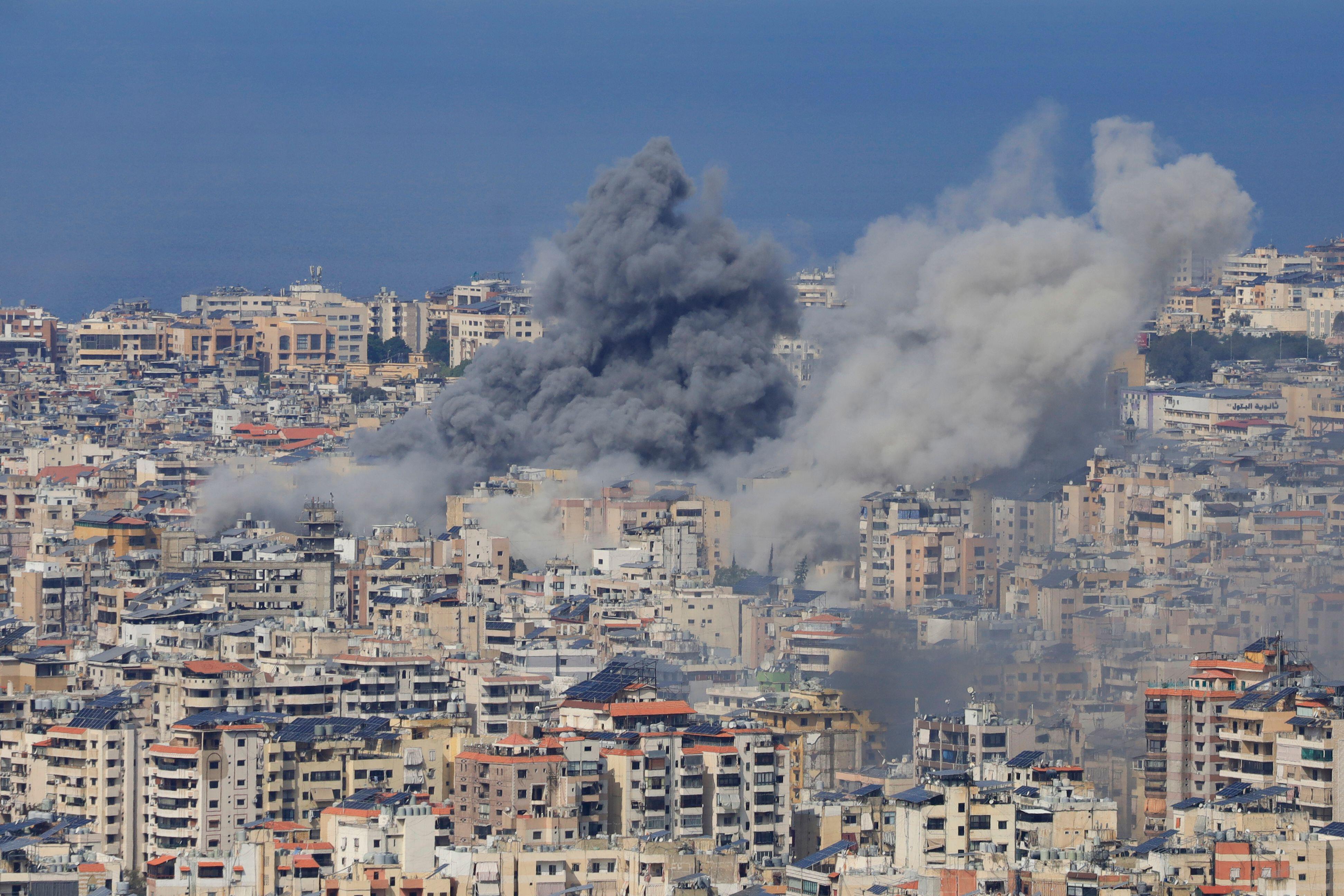 Wide shot of Beirut, during the day, smoke coming up of the building after an airstrike