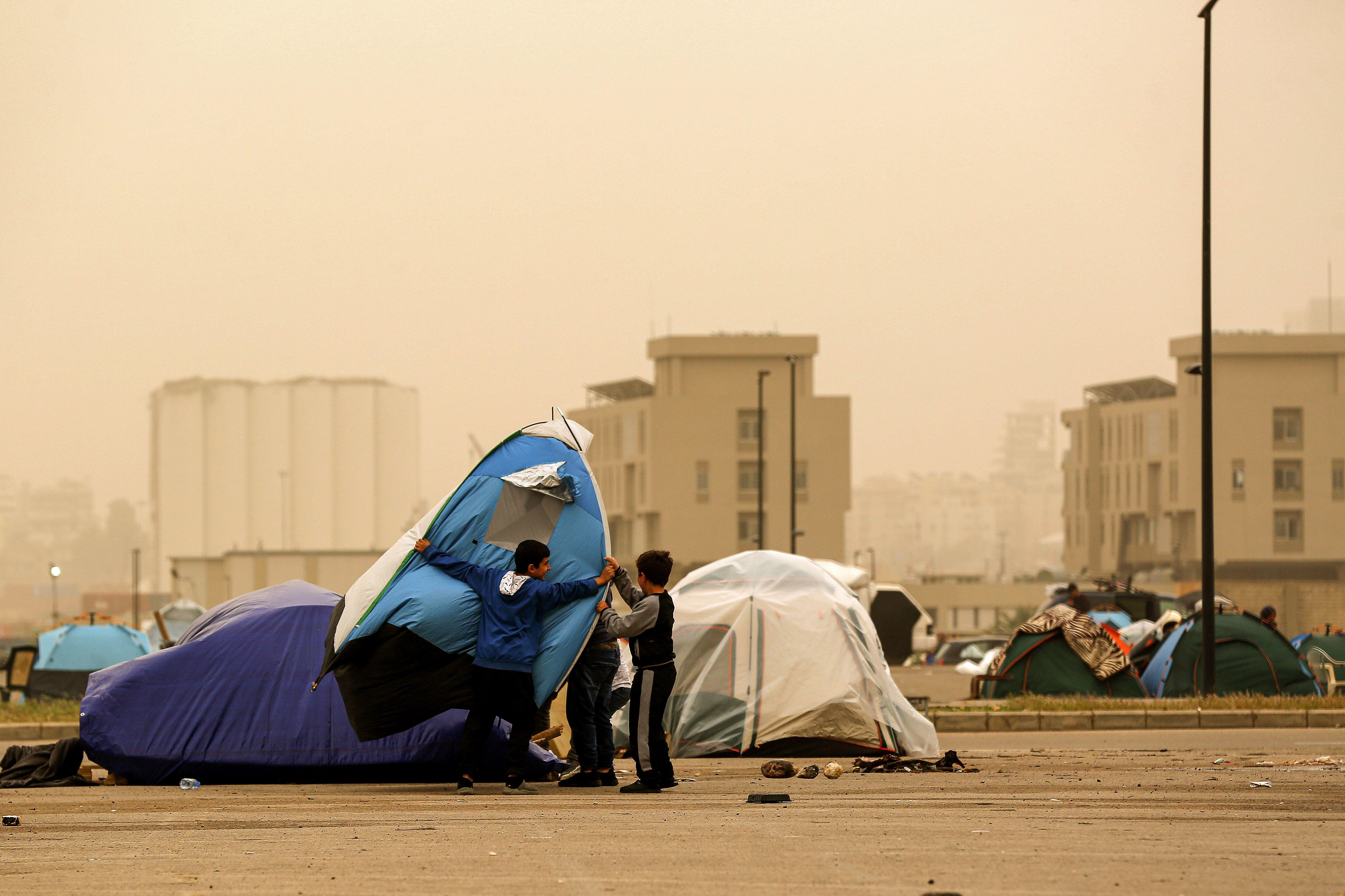 Beirut, Beirut, Lebanon. 14th Mar, 2026. Displaced children protect their tent from flying during a sand storm that engulfed Beirut. Over 800,000 have been forced to flee their homes in the south Lebanon and Beirut southern suburb, following blanket Israeli evacuation orders.