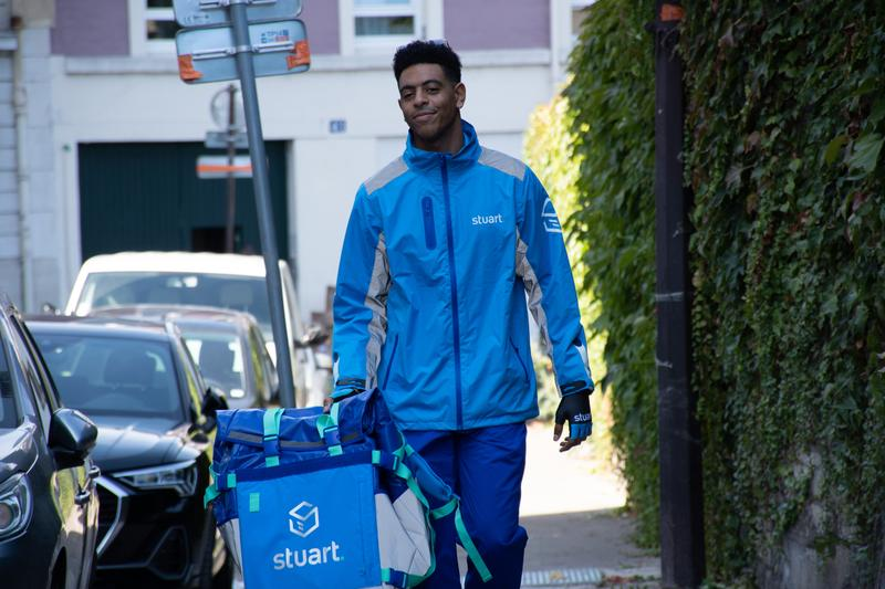 Black man with a blue jacket and a blue delivery box