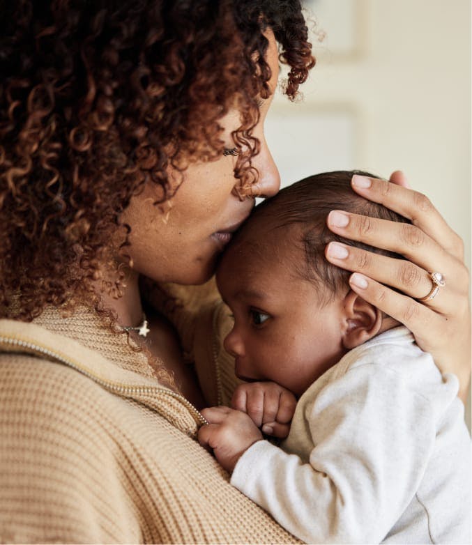 Close up of woman kissing a baby's forehead.