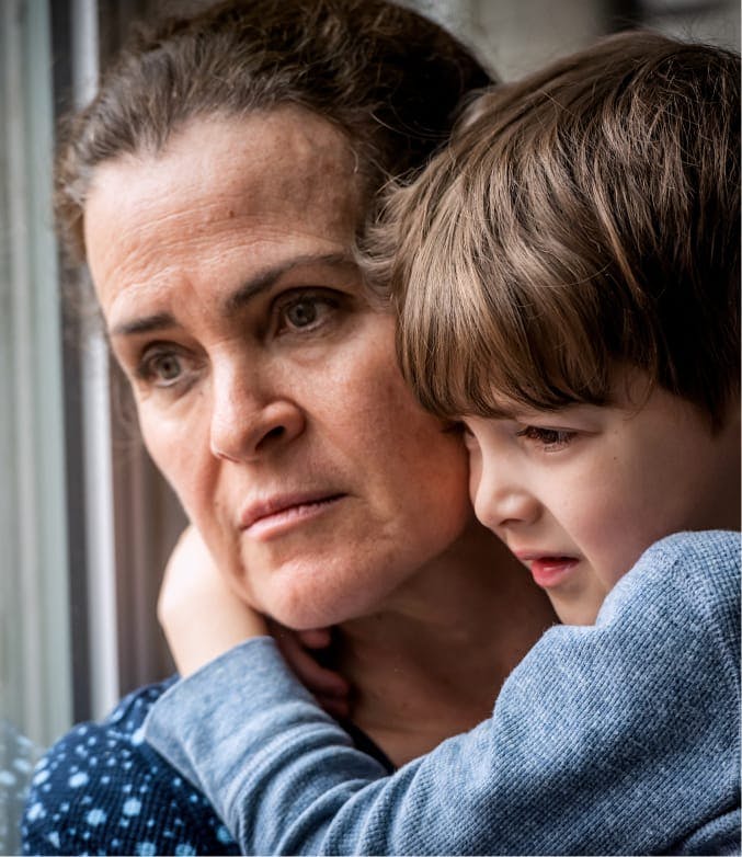 Woman looking forlorn while holding a young boy.