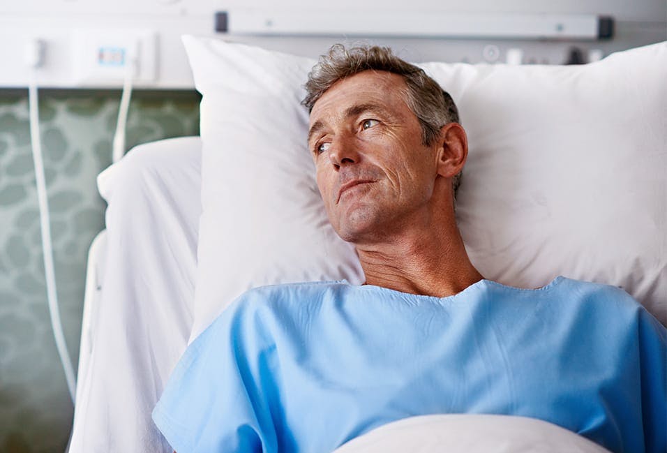 forlorn man looking out the window from a hospital bed