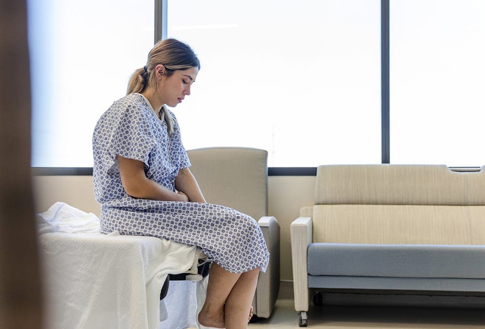 Sad woman in a hospital bed and gown