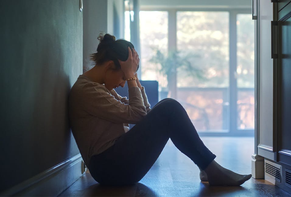 Woman sitting on the floor holding her head