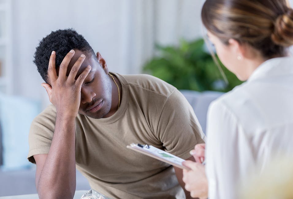 upset man holding his head while someone takes notes