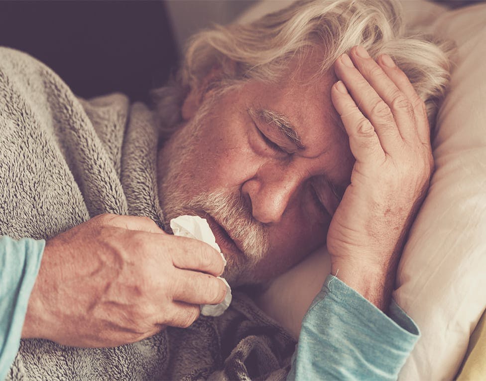 elderly man coughing into a napkin