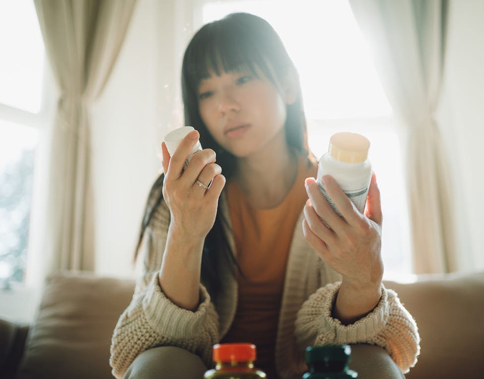 Woman looking at two bottles of pills