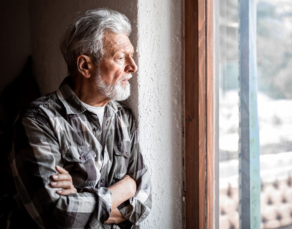 Elderly man looking out the window