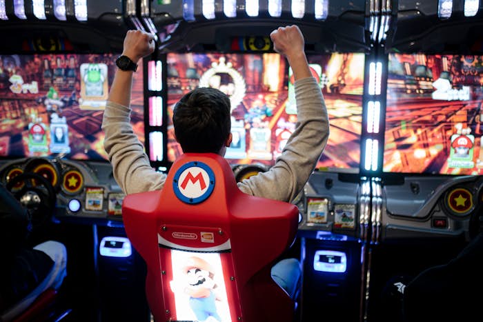 Man celebrating while playing Mario Kart arcade game