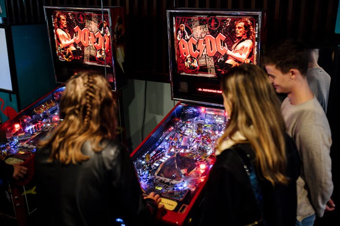 A group of people playing ACDC themed pinball