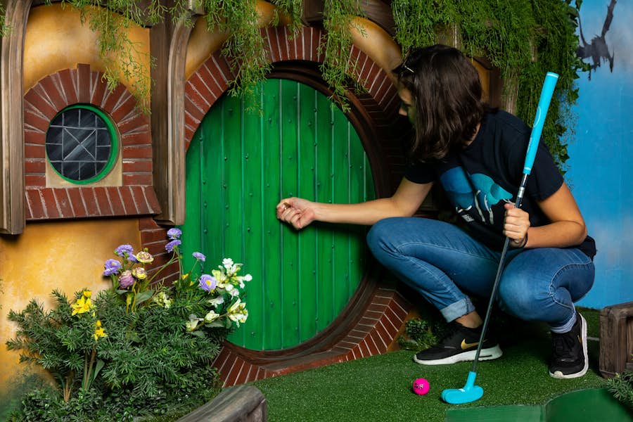 Woman pretending to open a Hobbit Hole door on the Lord of the Ring themed golf hole