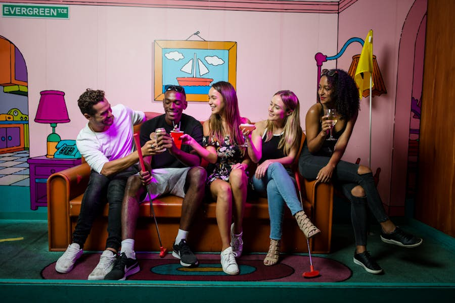 Group sitting on Simpsons couch with cocktails