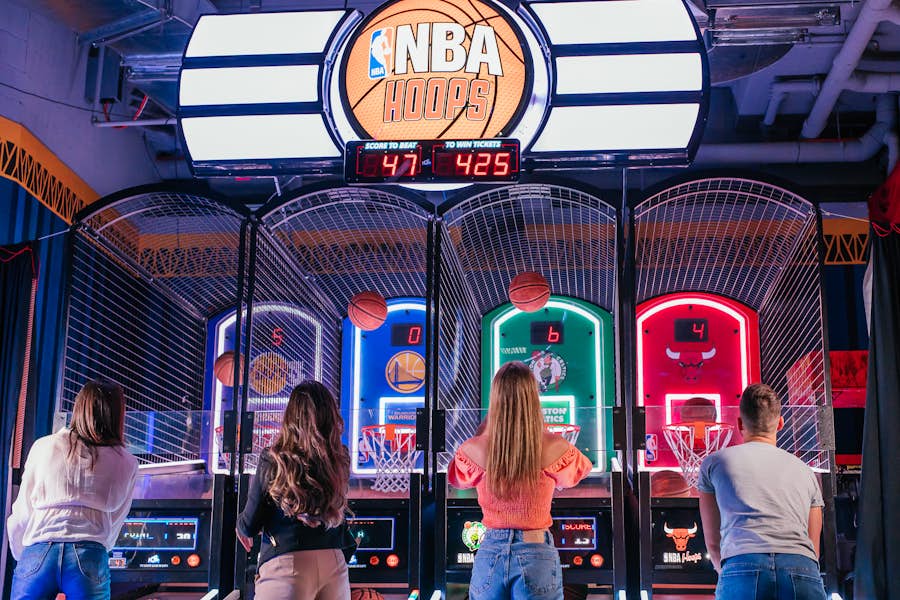 Four people playing the NBA Hoops arcade game at Archie Brothers Cirque Electriq.