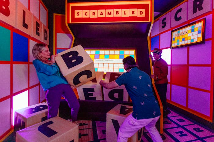 Two people sorting through the large letters to solve the clue in the scrambled challenge room.