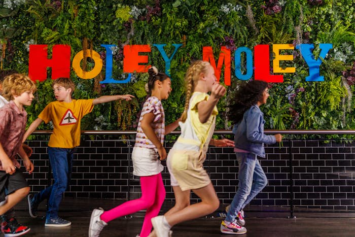Group of children running in front of Holey Moley sign