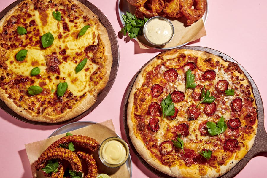 Two pizzas, corn ribs and onion rings