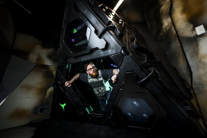 Person crawling out of the 'spaceship' in the Alien Invaders escape room.