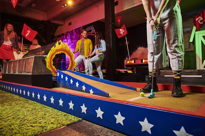 girl playing mini golf on our Tee-vel Knievel Hole as friends watch