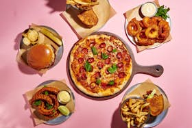 Selection of food offerings at Funlab venues on a pink background including; pizza, burgers, corn ribs, fries and onion rings.