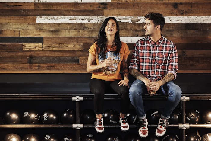 Man and woman sitting over bowling ball racks talking